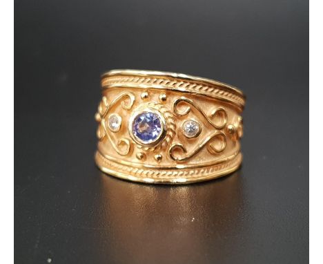 DIAMOND AND BLUE GEM SET RINGthe gemstones in wide scroll decorated fourteen carat gold band, ring size O-P and approximately