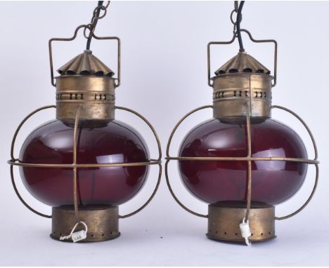 A pair of vintage mid 20th century circa 1960s brass &amp; glass ships oil hanging lamps lights. Each light having a dark red