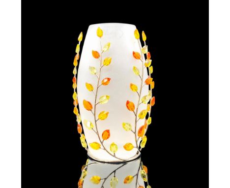 A frosted crystal vase with a metal base that has yellow, orange, and amber colored crystal leaves to create a branch pattern