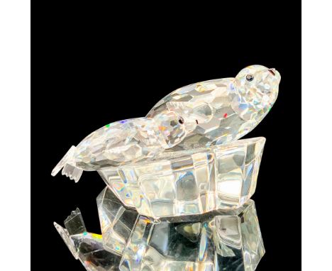 A clear crystal figure depicting a mother seal and her cub resting together on an ice block. Swarovski backstamp. This item h