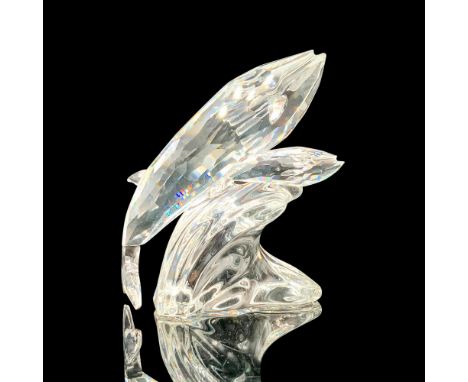 A clear crystal figure depicting a mother whale and her calf riding on a wave, with blue crystals used for the eyes. Swarovsk