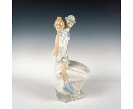 Glossy group figure of a seated young man and woman. The woman shyly looks away while the man hiding flowers behind his back.