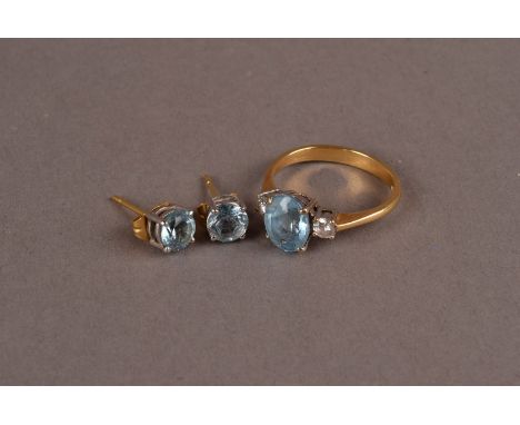 A modern 18ct gold and aqua marine ring and earrings, the three stone ring set with an oval light blue stone flanked by a pai