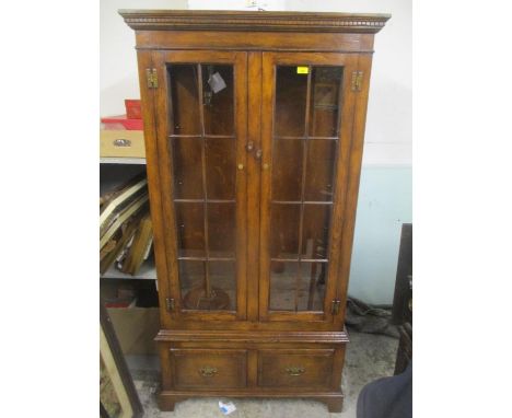 A reproduction oak glazed two door display cabinet with two drawers below and on bracket shaped feet 176.5h x 91.5cm w 