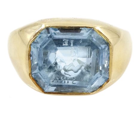 Early 20th century 18ct gold bezel set octagonal cut aquamarine intaglio ring, with Cupid as a blacksmith forging two hearts,