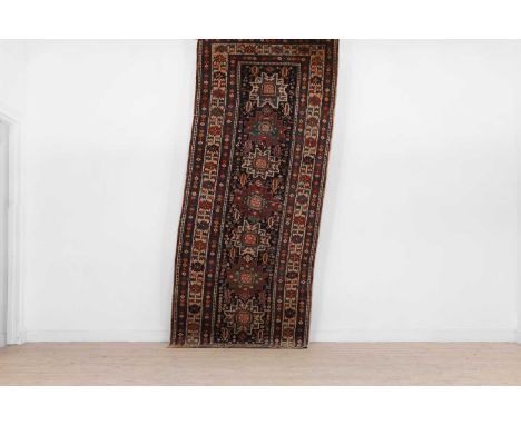 A Shirvan wool runner,  c.1920, East Caucasian, woven with repeating geometric motifs to a blue ground,  293 x 118cm  Conditi