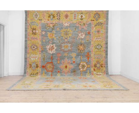 An Oushak wool carpet,  of recent manufacture, Turkish, woven with bold floral medallions to a pastel blue ground,425 x 300cm