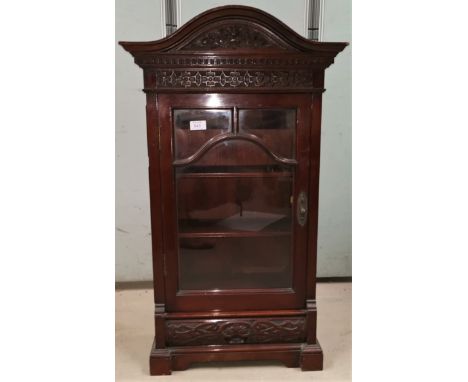 A small Edwardian carved mahogany wall cupboard with arch pediment and glazed door 