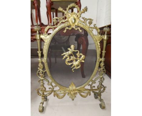 An ornate gilt metal firescreen with acanthus scrolls and cherub mounts 
