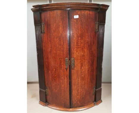 A Georgian oak bow front corner cupboard with moulded cornice and reeded side pillars, enclosed by 2 doors, height 40" 