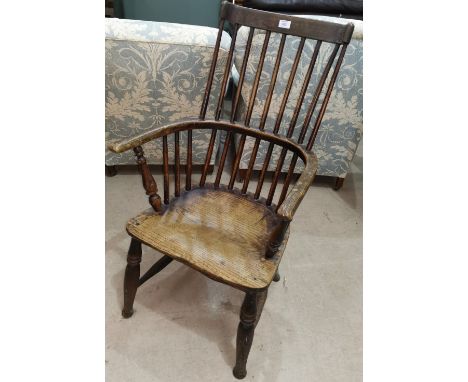 A 19th century elm Windsor armchair with comb back and solid seat, on peg legs 