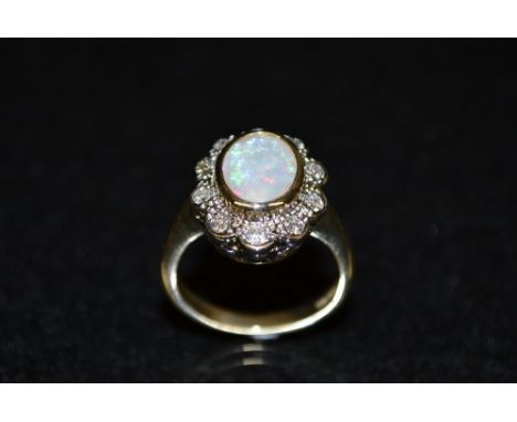 An opal and diamond cluster ring, central oval opal surrounded by a band of ten diamond accents, 9ct gold shank, size N 1/2, 