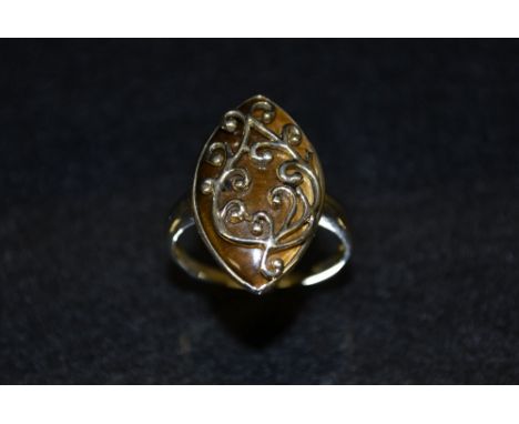 An tigers eye dress ring, navette tigers eye wrapped within a floral scrolling crest and plain surround, 9ct gold shank, size