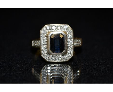 A sapphire and diamond cluster dress ring,  central rectangular cushion cut blue sapphire, inclosed collet, surrounded by a b