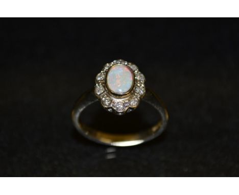 An opal and diamond cluster ring, central oval opal surrounded by a band of ten diamond accents, 9ct gold shank, size N, 3.1g