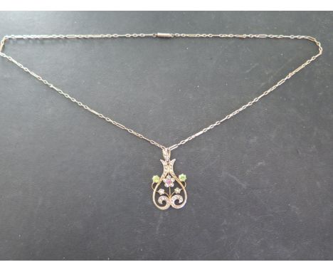 A 9ct yellow gold art nouveau pendent set with ruby, peridots and seed pearls on a 9ct yellow gold chain, length 50cm - in ge