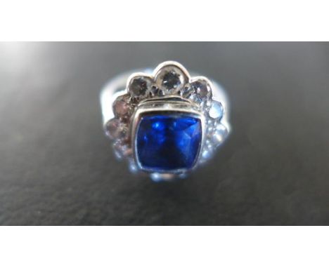 An 18ct white gold ring with large rectangular cut sapphire to centre, surrounded by twelve circular cut diamonds - light scr