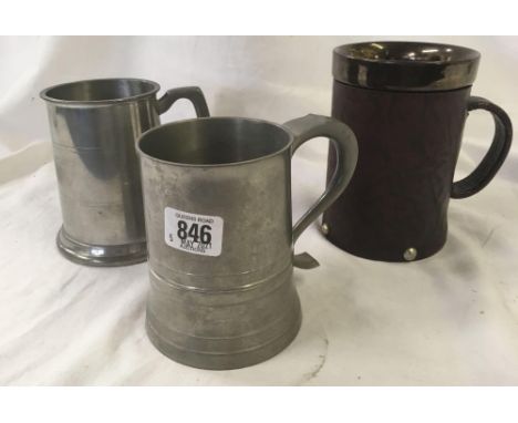 SHELF WITH 2 MODERN PEWTER MUGS, THIMBLE DISPLAY IN GLASS CASE, LEATHER BODIED MUG &amp; 2 BRASS ITEMS