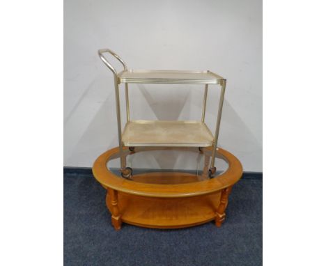 An oval glass topped coffee table with under shelf together with a gilt two tier tea trolley  