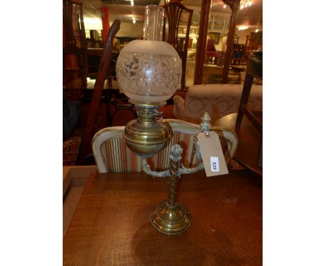 A Victorian brass oil lamp with spherical shade and flume