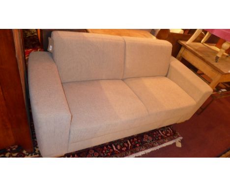 A contemporary designer John Lewis two seater sofa upholstered in beige mottled fabric and raised on block supports 