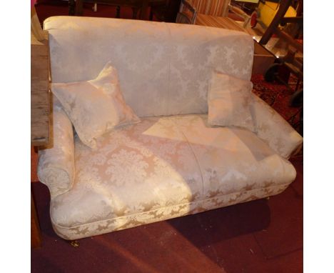 A Victorian style two seater sofa upholstered in ivory foliate damask raised on turned supports and castors