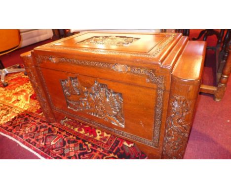 An Oriental profusely carved rosewood and camphorwood lined trunk, having figures in landscapes in relief