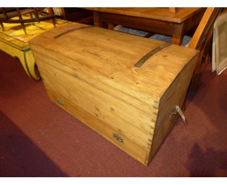 An antique pine and metal bound dome top trunk with twin handles and a base drawer 