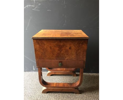 An Art Deco walnut work table, the hinged top opening to reveal a silk lined interior with drawer below, raised on sleigh bas