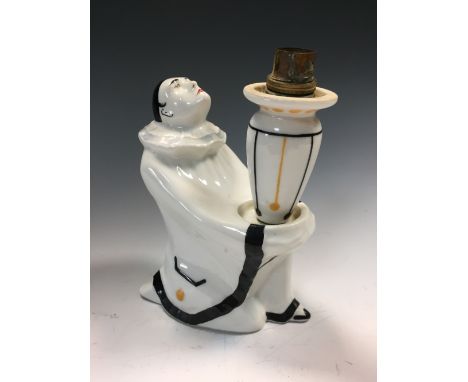 A Limoges lamp base by Elté modelled as Pierrot, he sits clasping a column supporting the light fitting, printed and painted 