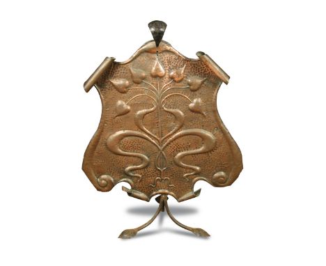 An Arts and Crafts copper fire screen, the repoussé shield embossed with stylised foliate motifs to a scrolling wrought iron 