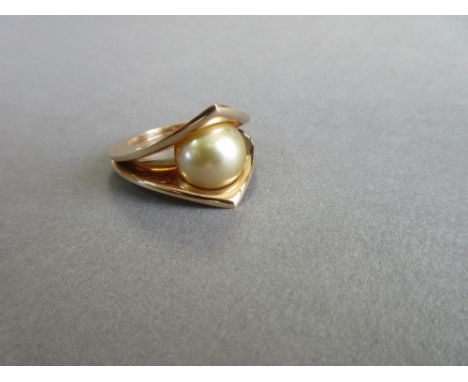 A single stone golden South Sea cultured pearl and 18ct gold ring by Paul Spurgeon, the 12mm pearl swivelling freely between 