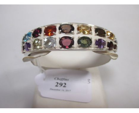 A multi-gemset hinged bangle, the broad tapering bangle half set with two rows of mixed faceted gemstones to include topaz, a