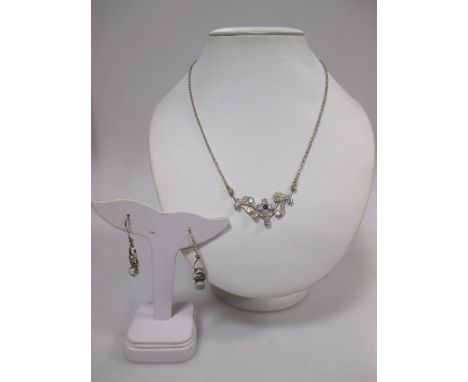 An Arts and Crafts style moonstone and silver necklace, the central moonstone cabochon and sapphire flower set to either side