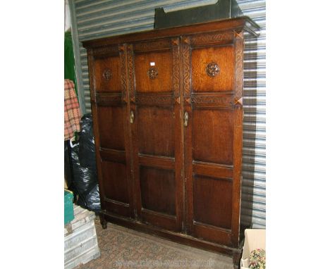 A 1940's Oak triple Wardrobe having three full length, three panel doors, each having upper carved panel with Tudor rose moti