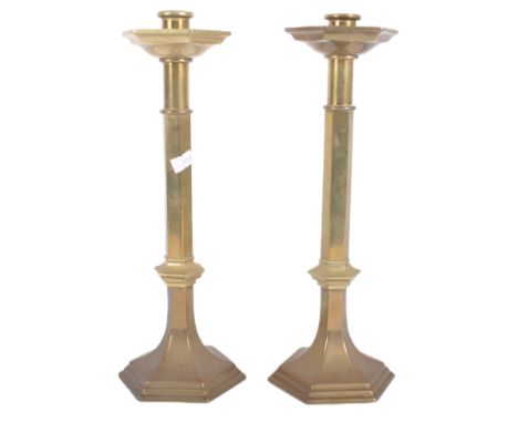 A matching pair of mid 20th Century solid brass candlestick holders of ecclesiastical influence having hexagonal trip tray to