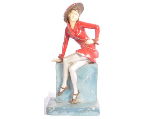 A vintage 20th Century Art Deco hand painted plaster figure in the form a well dressed lady perched upon a ledge. Painted wit