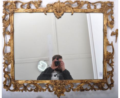 A vintage 20th Century giltwood framed hanging mirror having a foliate and scrolled open frame housing a central mirrored pla