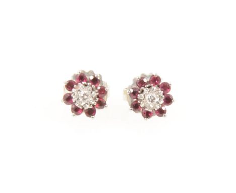 A pair of ruby and diamond ear studs, a brilliant cut diamond illusion set and surrounded by eight round rubies claw set in w