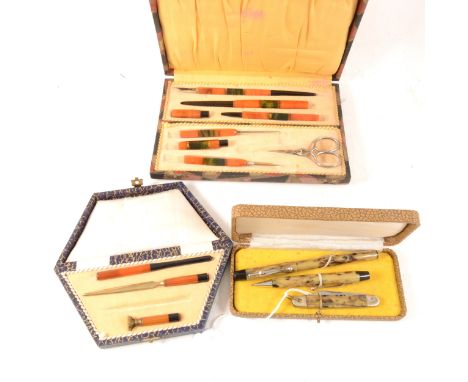 Two Art Deco Bakelite part writing sets and another "Foreign" three piece set, a part set in orange, black and green amber co