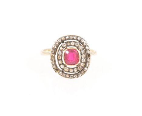 A diamond ring with ruby coloured stone to centre, forty-two old, rose and eight cut stones set in a double oval frame to a r