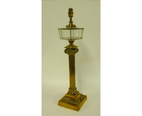 A brass doric column oil lamp, now converted to electricity, with glass reservoir and square base, with shade, 59cm to top of