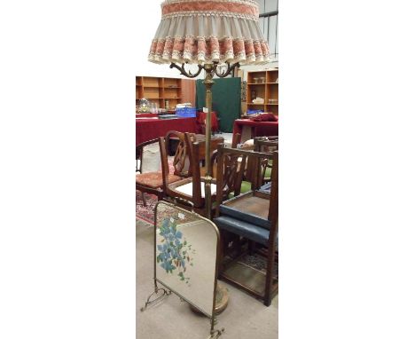 A brassed standard lamp on circular base with three claw feet, a brass framed mirrored fire screen and three prints.