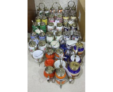 A collection of sixteen ceramic and glass three-piece cruet sets on plated stands, (16).