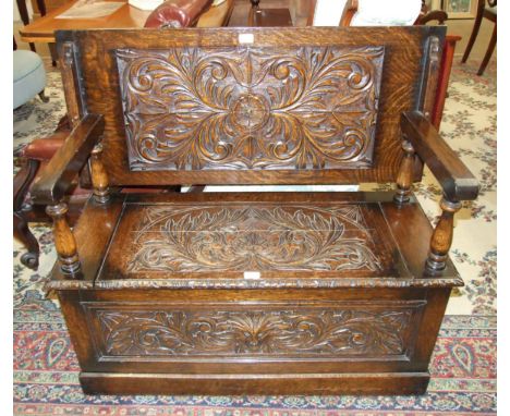 A mid-20th century oak monk's bench with carved decoration to top, seat and front, 106.5cm wide.