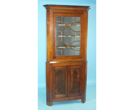 A Georgian mahogany corner cupboard, the moulded cornice above an astragal-glazed door and a pair of panelled doors, on later