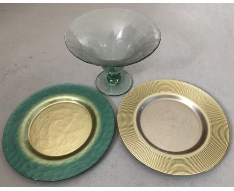 A green glass fruit bowl together with 2 green and gold glass chargers. Tiny nibble to rim of bowl. Bowl approx. 21cm tall an