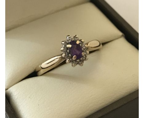 A 9ct gold dress ring set with central amethyst surrounded by 11 small diamonds. Size P. 