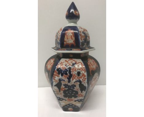 An oriental ceramic ginger jar of blue and orange colouration. Conical decoration to lid. Approx 3cm tall including lid.
