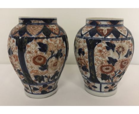A pair of oriental ceramic pots of blue and orange colouration with chrysanthemum panel design.  Approx. 14.5cm tall.